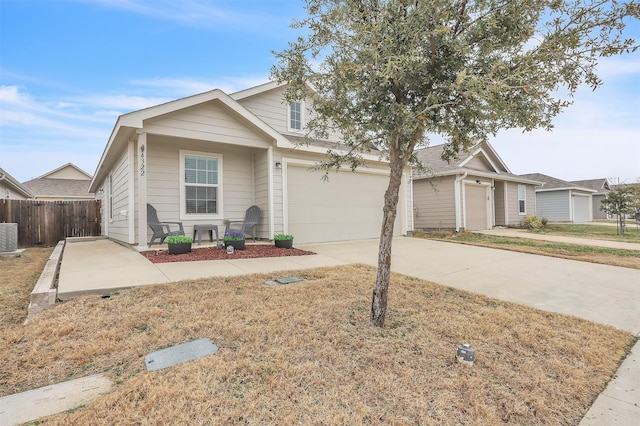 view of front facade with central AC unit, concrete driveway, an attached garage, and fence