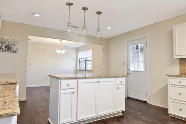 kitchen featuring light stone counters, decorative light fixtures, dark wood-type flooring, and white cabinets