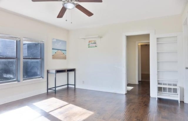 spare room featuring built in shelves, ceiling fan, and dark hardwood / wood-style floors