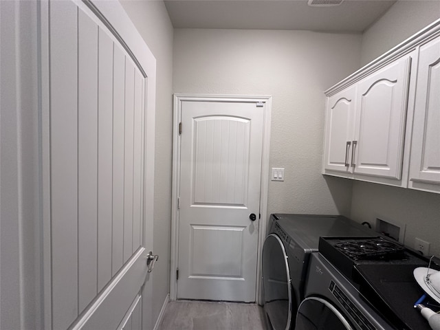 laundry room with cabinets, washing machine and dryer, and light hardwood / wood-style flooring