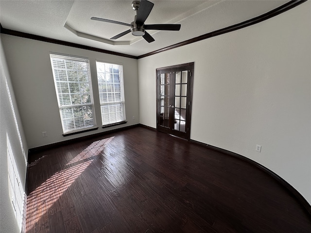 spare room with crown molding, dark wood-type flooring, ceiling fan, a tray ceiling, and a textured ceiling