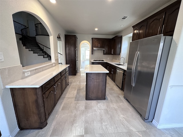 kitchen featuring sink, dark brown cabinets, stainless steel appliances, and a kitchen island