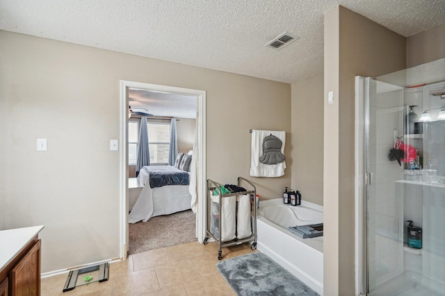 bathroom with tile patterned flooring, vanity, independent shower and bath, and a textured ceiling