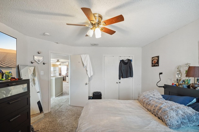 bedroom with ceiling fan, light carpet, a textured ceiling, and a closet