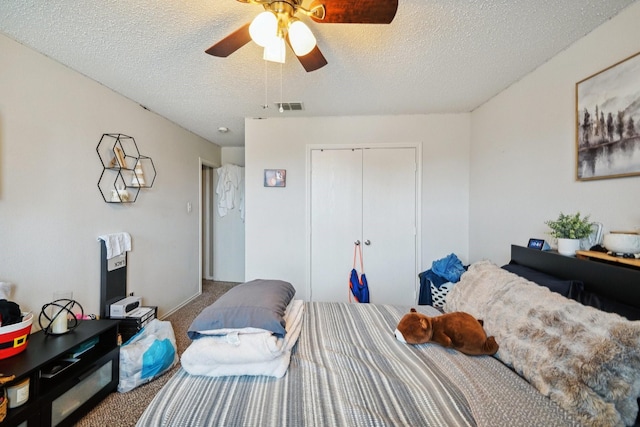 carpeted bedroom featuring ceiling fan, a closet, and a textured ceiling