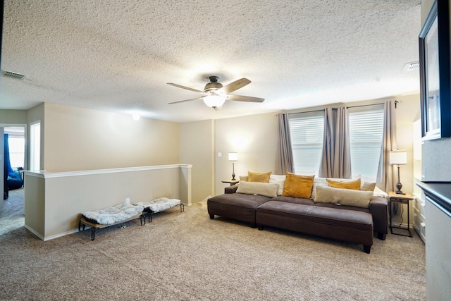 living room featuring ceiling fan, light colored carpet, and a textured ceiling