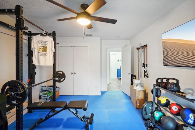 workout area with ceiling fan and a textured ceiling