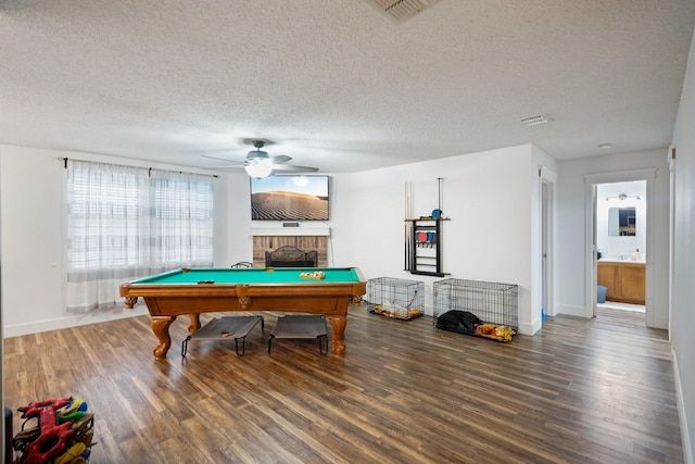 recreation room with pool table, a textured ceiling, hardwood / wood-style flooring, ceiling fan, and a fireplace