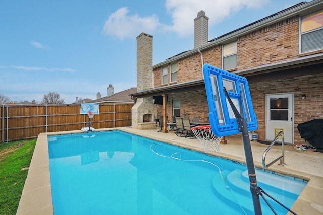 view of swimming pool with an outdoor fireplace and a patio