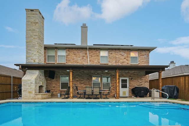 rear view of house with a fireplace and a patio