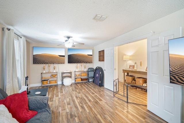 living room with hardwood / wood-style flooring, ceiling fan, and a textured ceiling