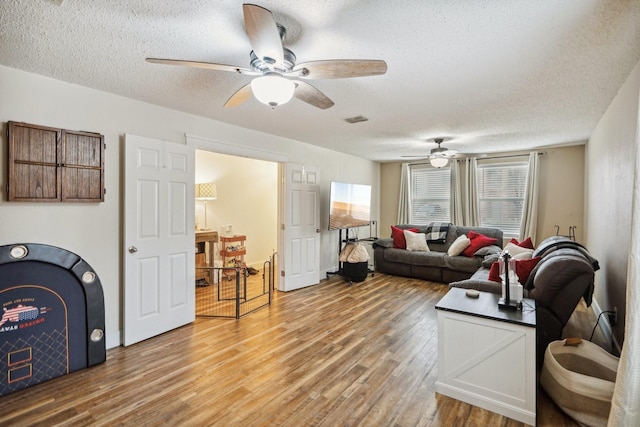 living room featuring ceiling fan, wood-type flooring, and a textured ceiling