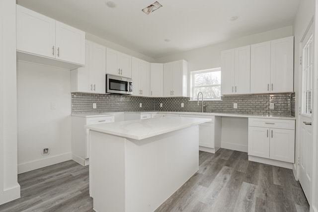 kitchen featuring backsplash, light hardwood / wood-style floors, a center island, and white cabinets