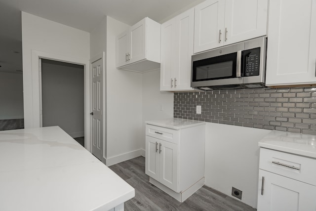 kitchen featuring hardwood / wood-style flooring, white cabinetry, light stone countertops, and backsplash