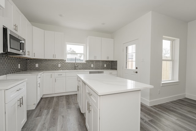 kitchen with sink, white cabinetry, a center island, light hardwood / wood-style floors, and decorative backsplash