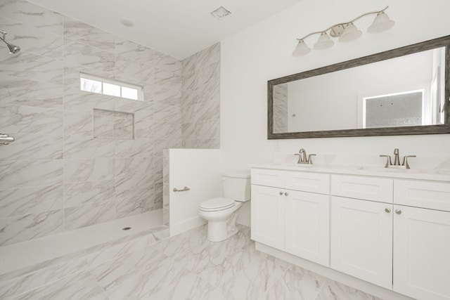 bathroom with tiled shower, vanity, and toilet