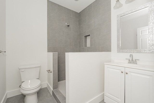 bathroom with a tile shower, vanity, tile patterned floors, and toilet