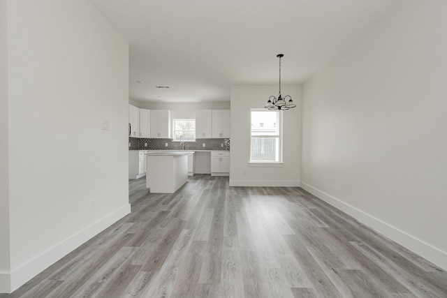 unfurnished living room featuring sink, a notable chandelier, and light hardwood / wood-style flooring