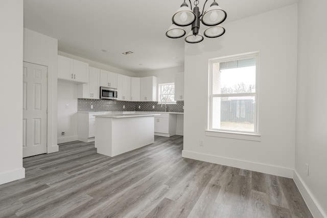 kitchen featuring a center island, tasteful backsplash, a notable chandelier, light hardwood / wood-style floors, and white cabinets