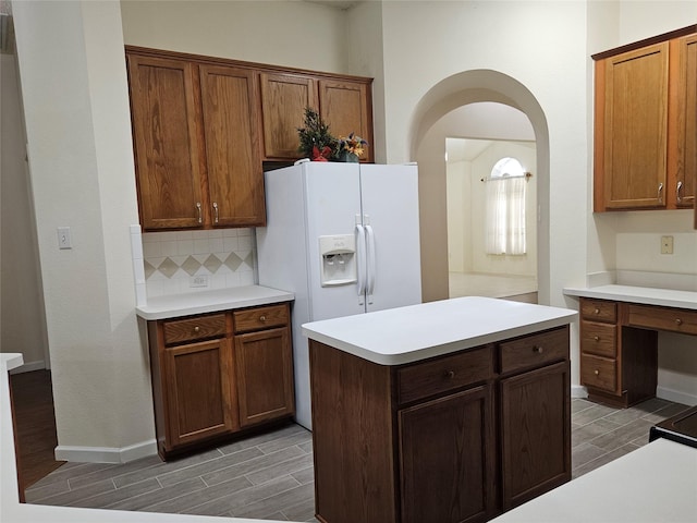 kitchen with a center island, white fridge with ice dispenser, and backsplash