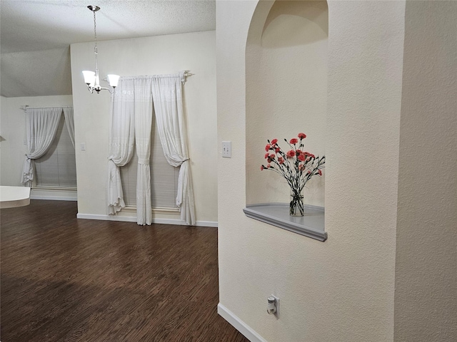 interior space featuring an inviting chandelier, dark hardwood / wood-style floors, and a textured ceiling