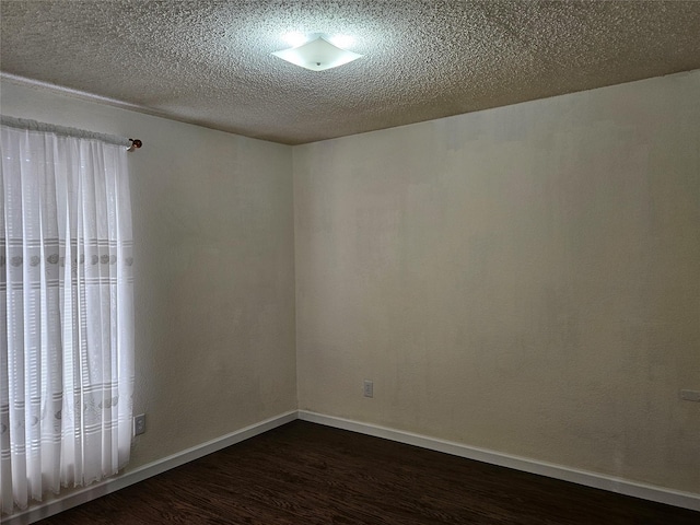 empty room with dark hardwood / wood-style floors and a textured ceiling