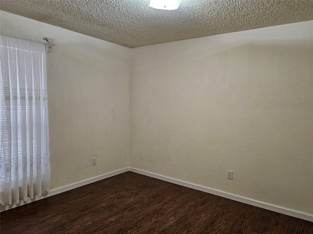 spare room featuring a healthy amount of sunlight, dark hardwood / wood-style floors, and a textured ceiling