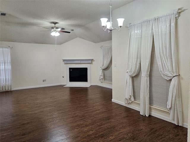 unfurnished living room featuring ceiling fan with notable chandelier, lofted ceiling, dark hardwood / wood-style flooring, a tiled fireplace, and a textured ceiling