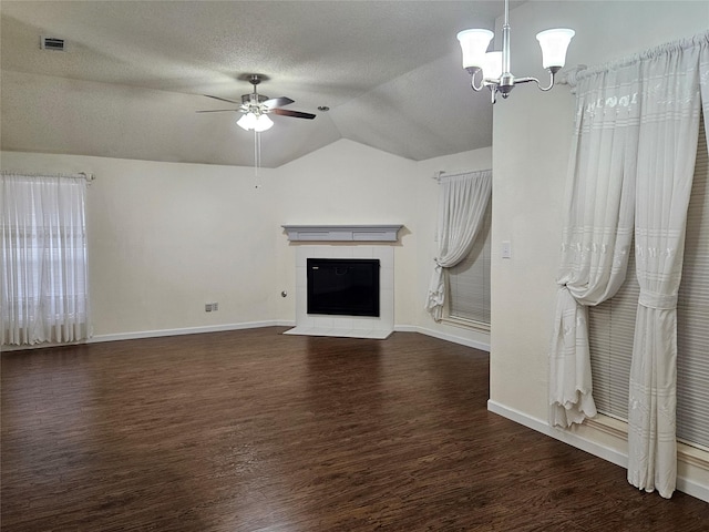 unfurnished living room with ceiling fan with notable chandelier, lofted ceiling, a tiled fireplace, dark wood-type flooring, and a textured ceiling