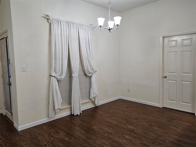 spare room with dark hardwood / wood-style floors and a notable chandelier