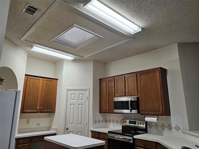 kitchen featuring stainless steel appliances, backsplash, and a textured ceiling