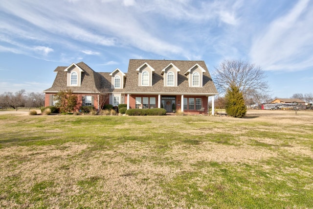 cape cod home with brick siding, roof with shingles, and a front lawn