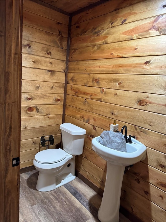 bathroom featuring wood-type flooring, toilet, and wood walls