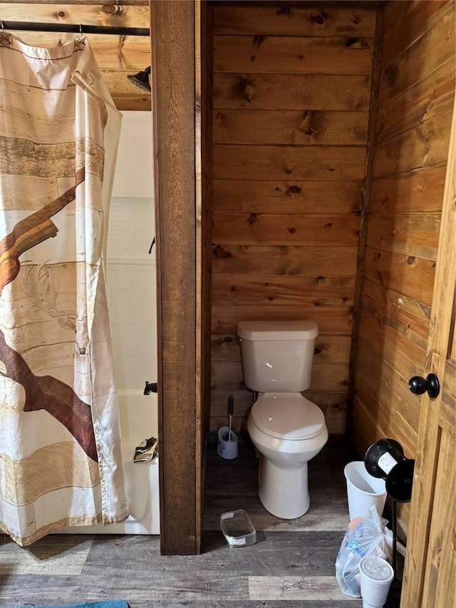 bathroom with wood-type flooring, wooden walls, and toilet