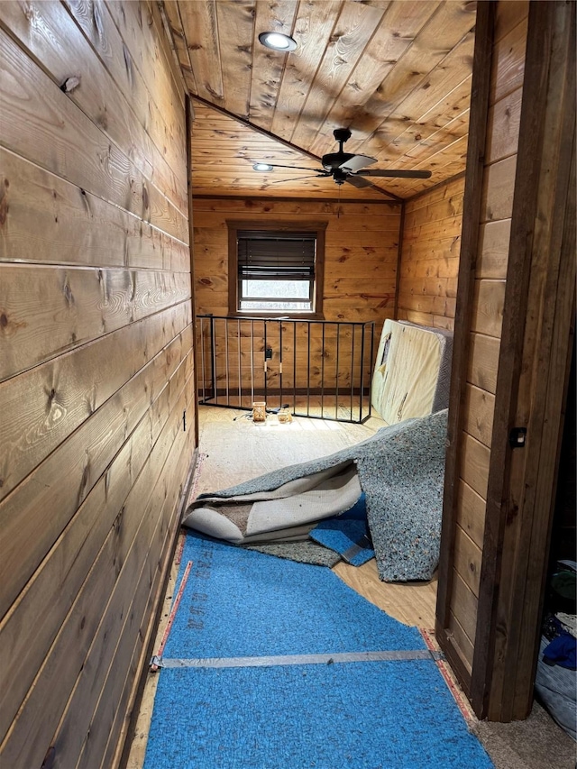 unfurnished room with wooden walls, wooden ceiling, and ceiling fan