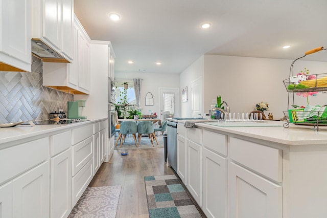 kitchen with tasteful backsplash, stainless steel appliances, light hardwood / wood-style flooring, and white cabinets