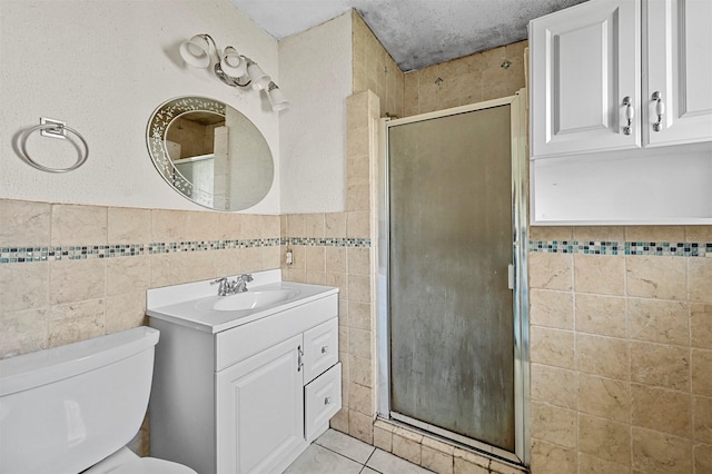 bathroom with vanity, a shower with door, toilet, and tile walls