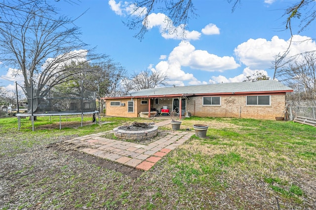 rear view of house with a fire pit, a patio, and a lawn