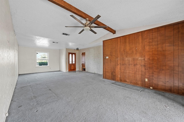 carpeted spare room with ceiling fan, vaulted ceiling with beams, and a textured ceiling