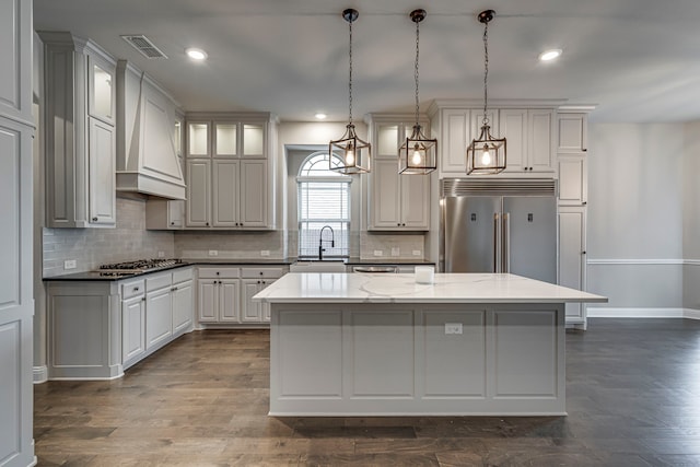 kitchen featuring a center island, sink, custom range hood, and white cabinets