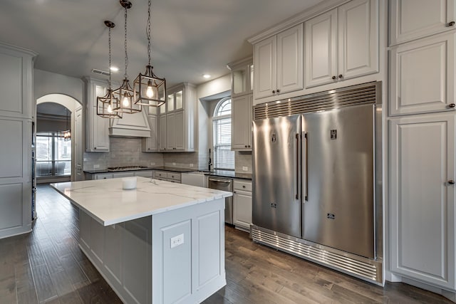 kitchen featuring a kitchen island, decorative light fixtures, white cabinets, decorative backsplash, and stainless steel appliances