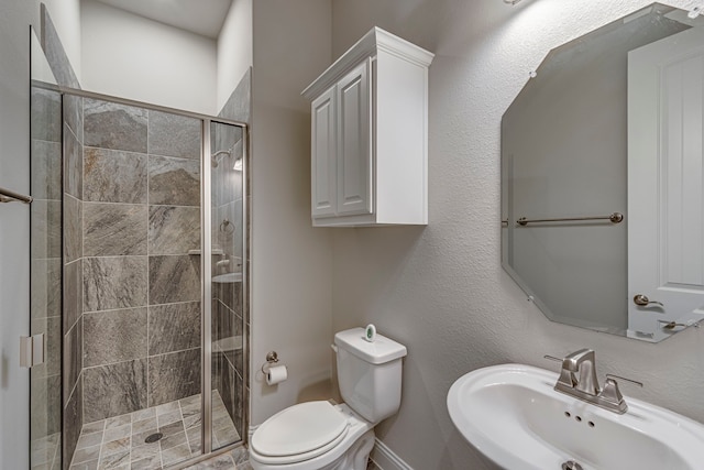 bathroom featuring toilet, a shower with shower door, and sink