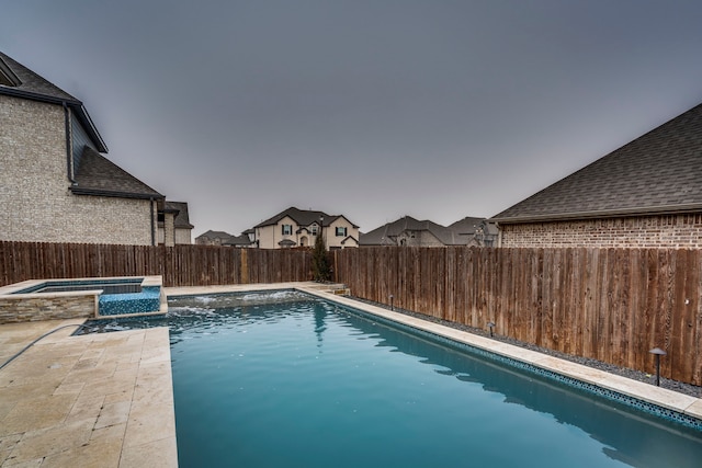 pool at dusk with an in ground hot tub