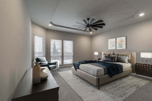 carpeted bedroom with a tray ceiling and ceiling fan