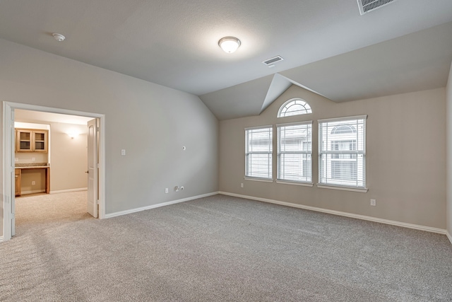 spare room featuring lofted ceiling and light carpet