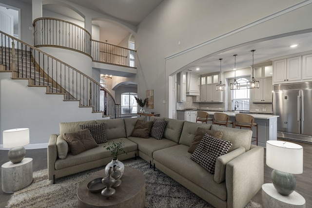 living room featuring a high ceiling, dark hardwood / wood-style floors, sink, and a notable chandelier