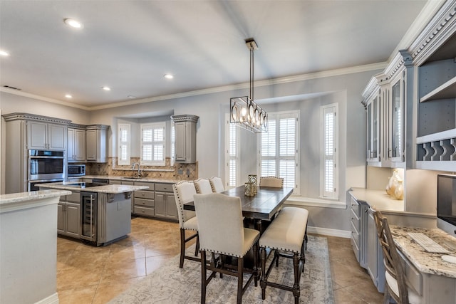 tiled dining space with a healthy amount of sunlight, sink, and ornamental molding