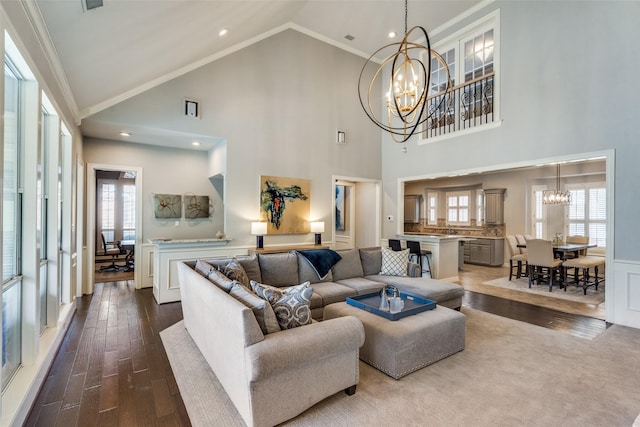 living room featuring an inviting chandelier, lofted ceiling, wood-type flooring, and crown molding