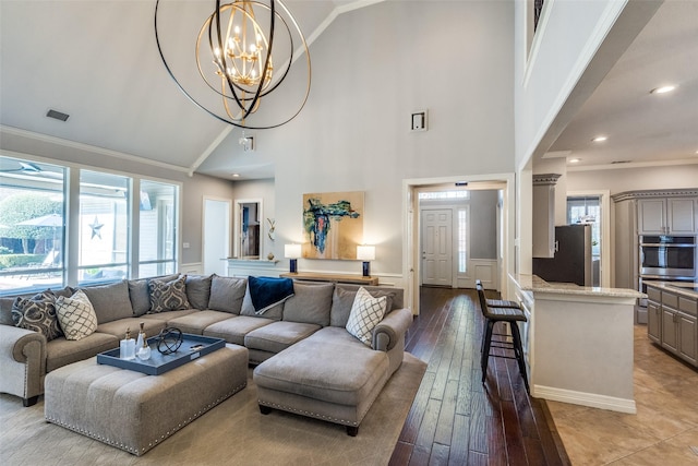 living room with a notable chandelier, light hardwood / wood-style flooring, ornamental molding, and a healthy amount of sunlight