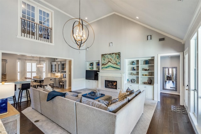 living room with a notable chandelier, hardwood / wood-style flooring, ornamental molding, and a brick fireplace